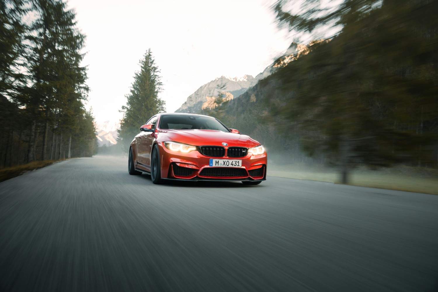 A sleek modern red sports car driving fast on a sunlit highway with blurred motion effect